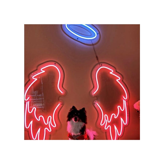 A dog sitting in front of a custom neon sign of angel wings, creating a captivating and heavenly scene